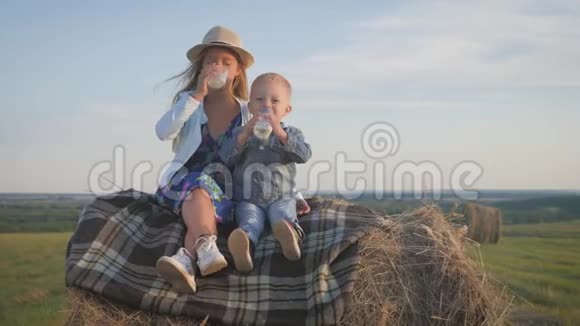日落时分弟弟和姐姐坐在田野的干草堆上喝牛奶视频的预览图