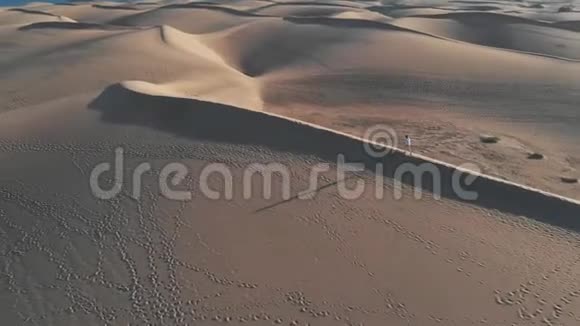 鸟瞰一个孤独的女孩走过沙漠日落时有一个长长的影子马斯帕洛马斯大加那利视频的预览图