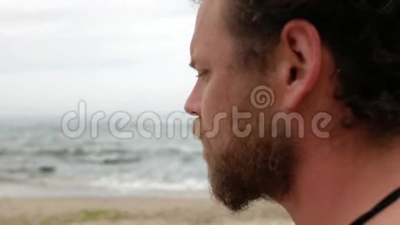 一个留着胡子和蓝眼睛的年轻人在海里游泳后有感情地对着镜头微笑4k录像男子视频的预览图