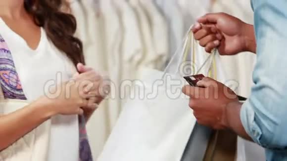 一位漂亮的黑发女郎在服装店用信用卡付款视频的预览图