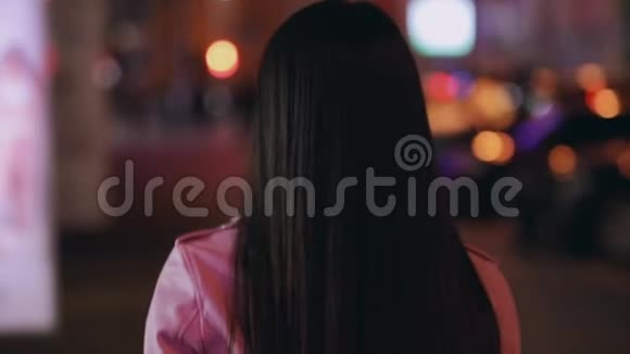 时髦的亚洲女人走在一个夜晚的城市里转脸回头看视频的预览图