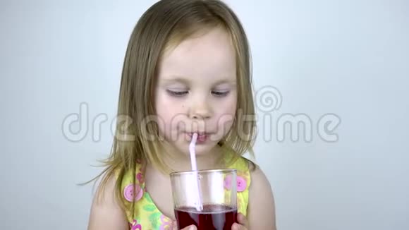 一个三岁的小女孩用吸管从杯子里喝果汁在白色背景下视频的预览图