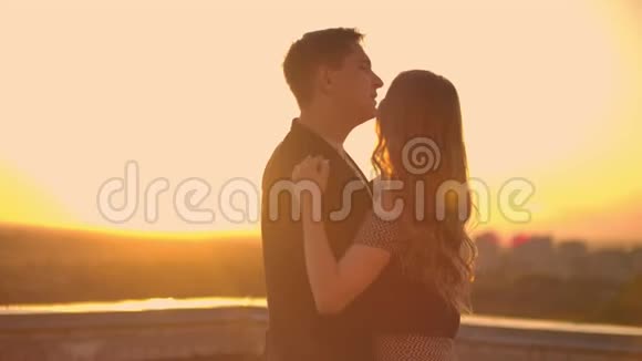 一对相爱的男人和一个女人站在建筑物的屋顶上看着日落视频的预览图
