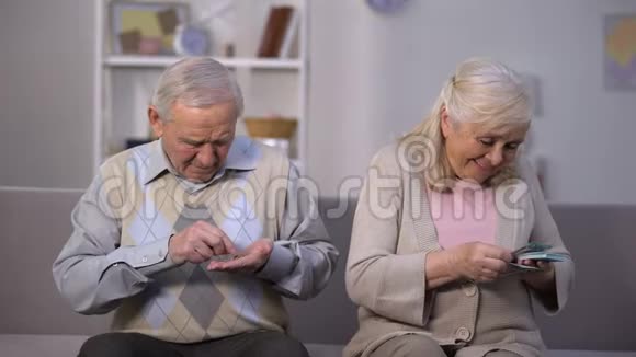 老人数着硬币看着幸福的老妇人计算美元财富视频的预览图