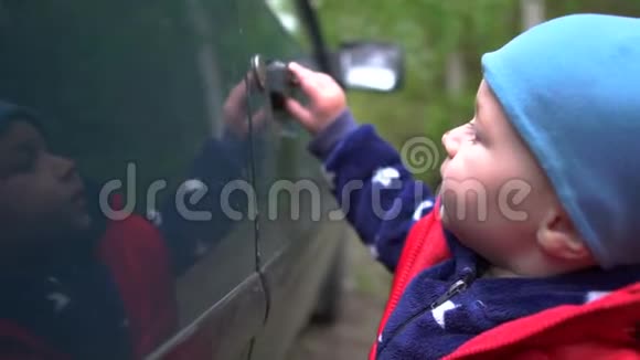 春天小男孩正试图在户外打开一扇旧车门视频的预览图