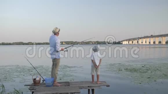 快乐的童年慈爱的爸爸在暑假期间和他亲爱的儿子在河边钓鱼视频的预览图