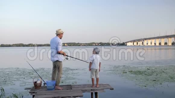 假期钓鱼父子俩戴着草帽手里拿着纺棒在河里钓鱼视频的预览图