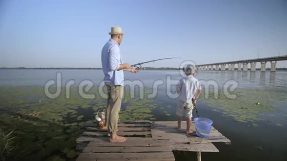 家庭周末快乐的父亲和小儿子戴着旋转棒的帽子在码头的暑假里玩钓鱼的乐趣视频的预览图