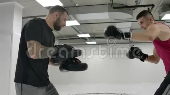 在混合战斗的训练中这个人跳起来时用教练的爪子拍膝盖慢动作视频的预览图