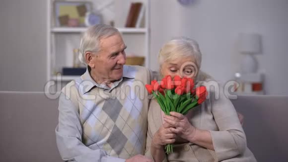 老人用郁金香拥抱快乐的女人爱人送的礼物视频的预览图