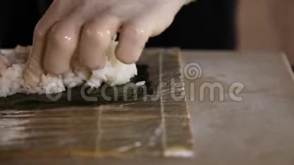 寿司师傅的特写镜头将米饭撒在诺丽身上寿司制作过程厨师的手视频的预览图