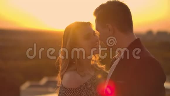 一对相爱的男人和一个女人站在建筑物的屋顶上看着日落视频的预览图