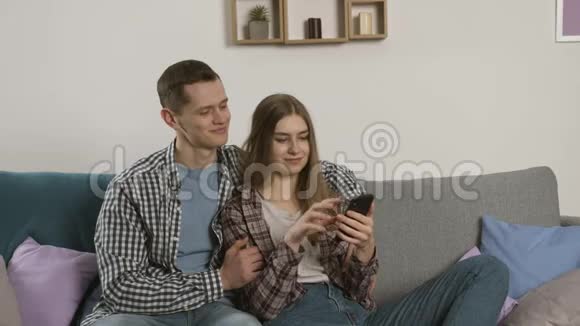 在客厅里一对幸福的情侣牵手使用智能手机视频的预览图
