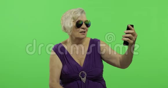 一位老年妇女正在用智能手机进行视频聊天彩色键视频的预览图