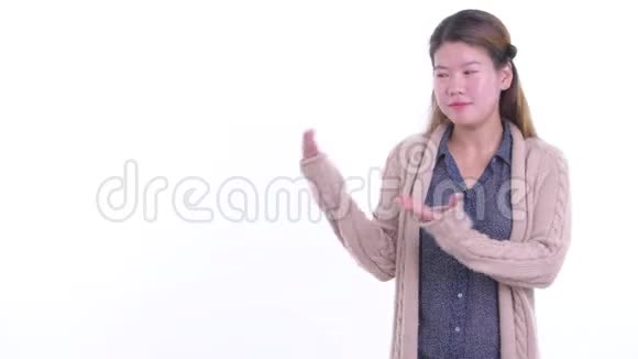 快乐的年轻亚洲女人一边说话一边展示准备过冬的东西视频的预览图