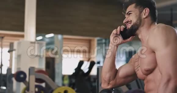 一个有魅力的人在体育课上锻炼身体的时候在电话里微笑着交谈视频的预览图