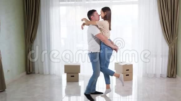 一对穿着蓝色牛仔裤的情侣在新房里拥抱亲吻视频的预览图
