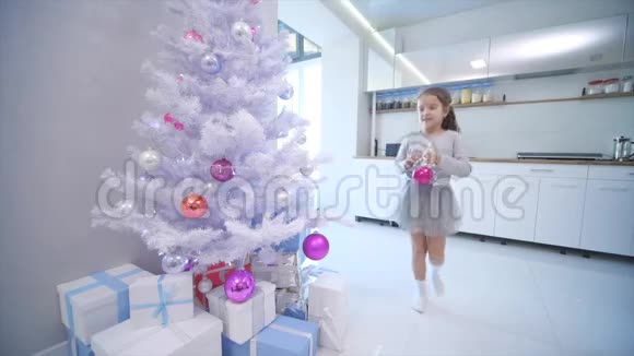 漂亮的小女孩走到最前面的圣诞树上在树枝上放了一个玻璃杯视频的预览图