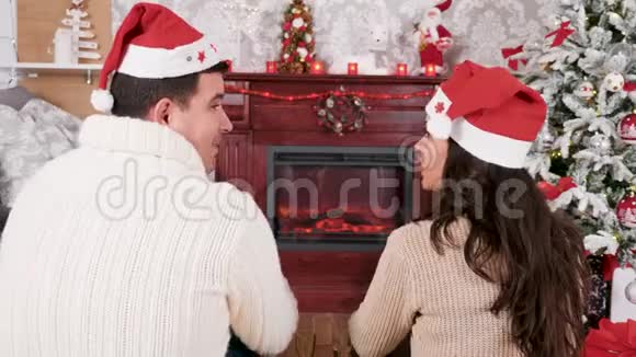 快乐的一对夫妇在壁炉前度过圣诞节喝着香槟视频的预览图