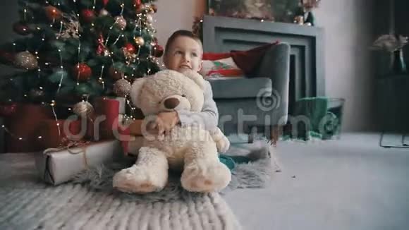 快乐的孩子带着泰迪熊坐在圣诞树旁视频的预览图