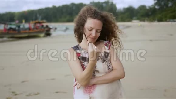 体贴的卷曲雌性站在海滩上视频的预览图