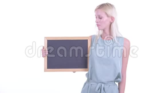 一个年轻的金发女郎站在黑板上竖起大拇指视频的预览图