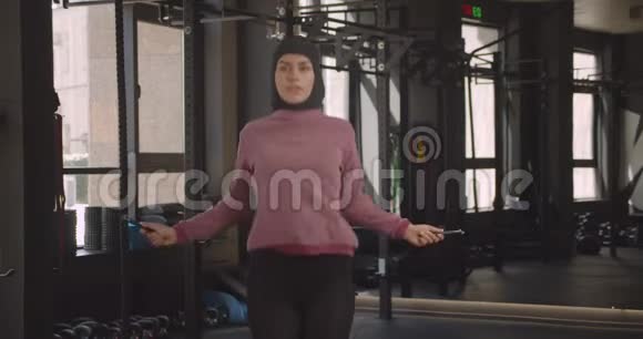 室内健身房中年轻迷人的穆斯林女性跳绳特写照片视频的预览图