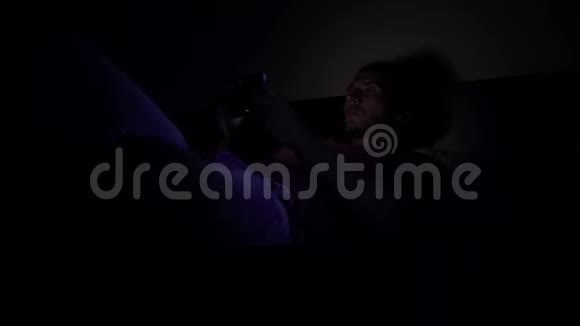 那家伙躺在黑暗的房间里的床上看着电话视频的预览图