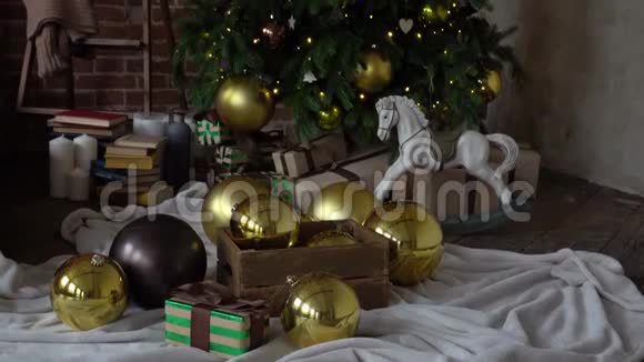 节日新年礼物盒和木制玩具在装饰的圣诞树下金色的鲍鱼花环在舒适的地方视频的预览图
