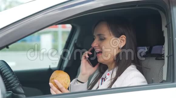 女人在车里吃午饭用手机视频的预览图