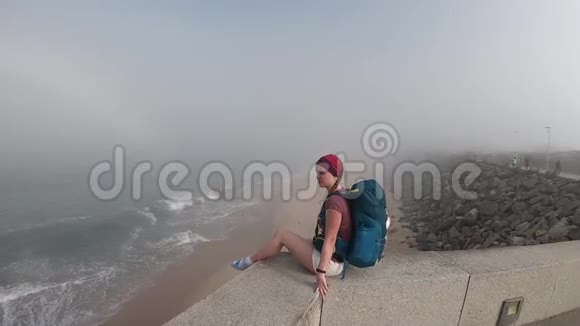葡萄牙的女人看着地平线和海洋葡萄牙帕沃瓦兹姆空滩秋日雾蒙蒙视频的预览图