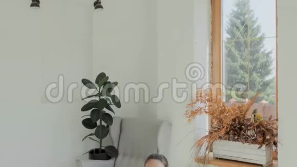 穿着运动服的年轻黑发女孩坐在莲花的姿态中在家冥想视频的预览图