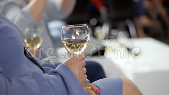 坐在活动现场的女士拿着一杯白葡萄酒一只手拿着玻璃特写视频的预览图