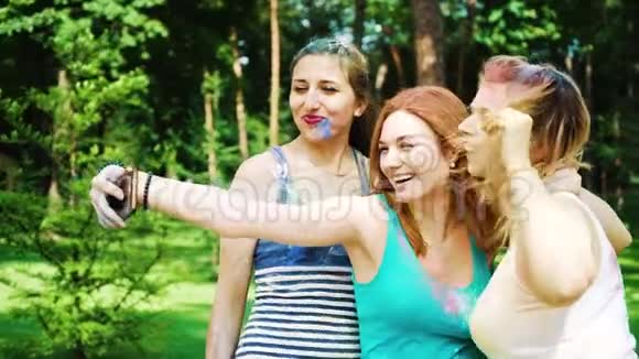 三个快乐的年轻女人在霍利画做滑稽的脸自拍照片视频的预览图
