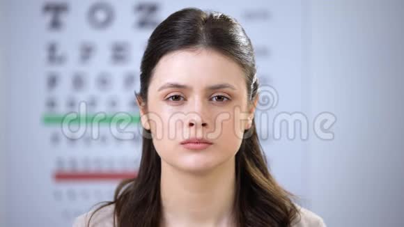 女性挤压眼睛眼科医生把折射镜放在微笑的女士病人身上视频的预览图