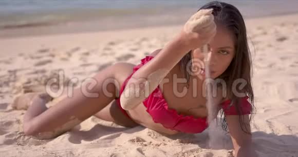 热的晒黑的女人沙滩上的沙子从手中流过让人放松视频的预览图