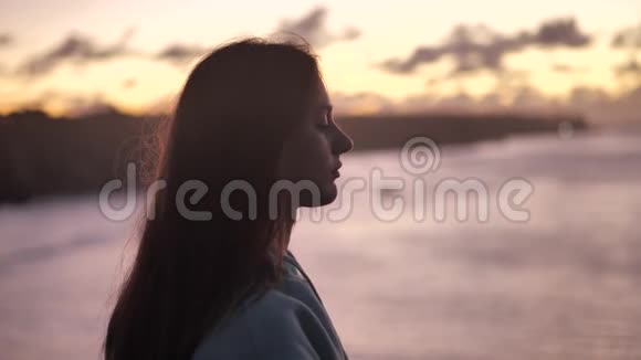 美丽的女孩祈祷仰望橙色的天空与希望特写年轻女子梦中的剪影视频的预览图