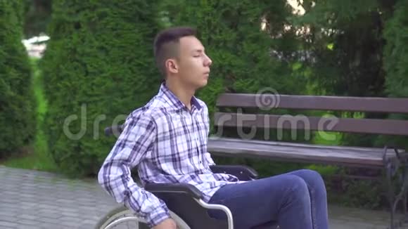 残疾的亚洲青年男子乘坐轮椅在公园慢莫视频的预览图