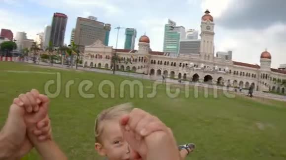 一个父亲在吉隆坡的梅德卡广场上旋转他的儿子的镜头旅费视频的预览图