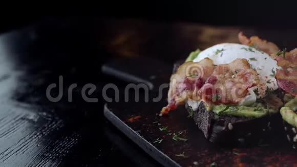 烤面包上有熏肉的蛋在黑色的石板上躺着主体进入框架视频的预览图