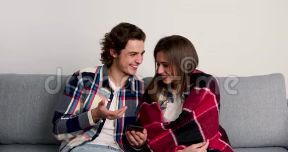 幸福的一对夫妇在客厅里用智能手机微笑着交谈视频的预览图