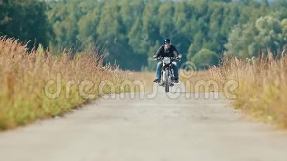 一个骑摩托车的男子骑着摩托车在尘土飞扬的麦田路上视频的预览图