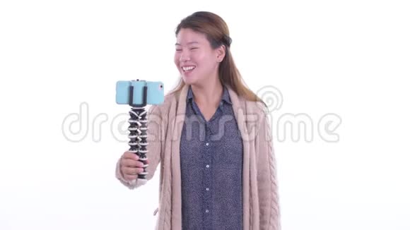 快乐的年轻亚洲女人在冬天打电话视频的预览图