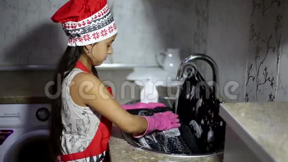 孩子们在厨房水槽里洗笔记本电脑穿红色围裙和粉红色手套清洗视频的预览图