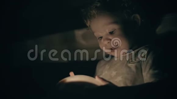 快乐的小宝宝在黑暗的房间里看着发光的突出玩具视频的预览图