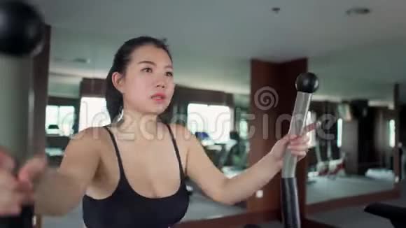 在健身俱乐部努力锻炼心脏椭圆运动的年轻美丽和出汗的亚洲韩国妇女的体操锻炼镜头视频的预览图