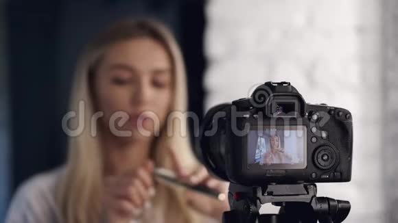 一架照相机正在拍摄化妆师正在做化妆教程视频的预览图
