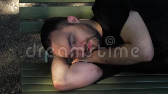 年轻人躺在公园的长凳上睡觉休息后醒来视频的预览图