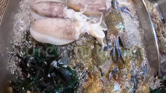 不同的新鲜海鲜在街头市场柜台螃蟹虾鱿鱼和章鱼冰上的鱼和贻贝视频的预览图
