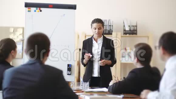 非洲裔美国女孩站在白板旁边用记号笔显示桌子上的工作人员该做什么视频的预览图